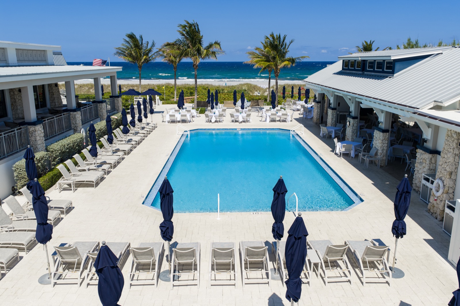 Aerial view of the Delray Beach Club pool deck, lounge chairs, and the Atlantic Ocean in the background